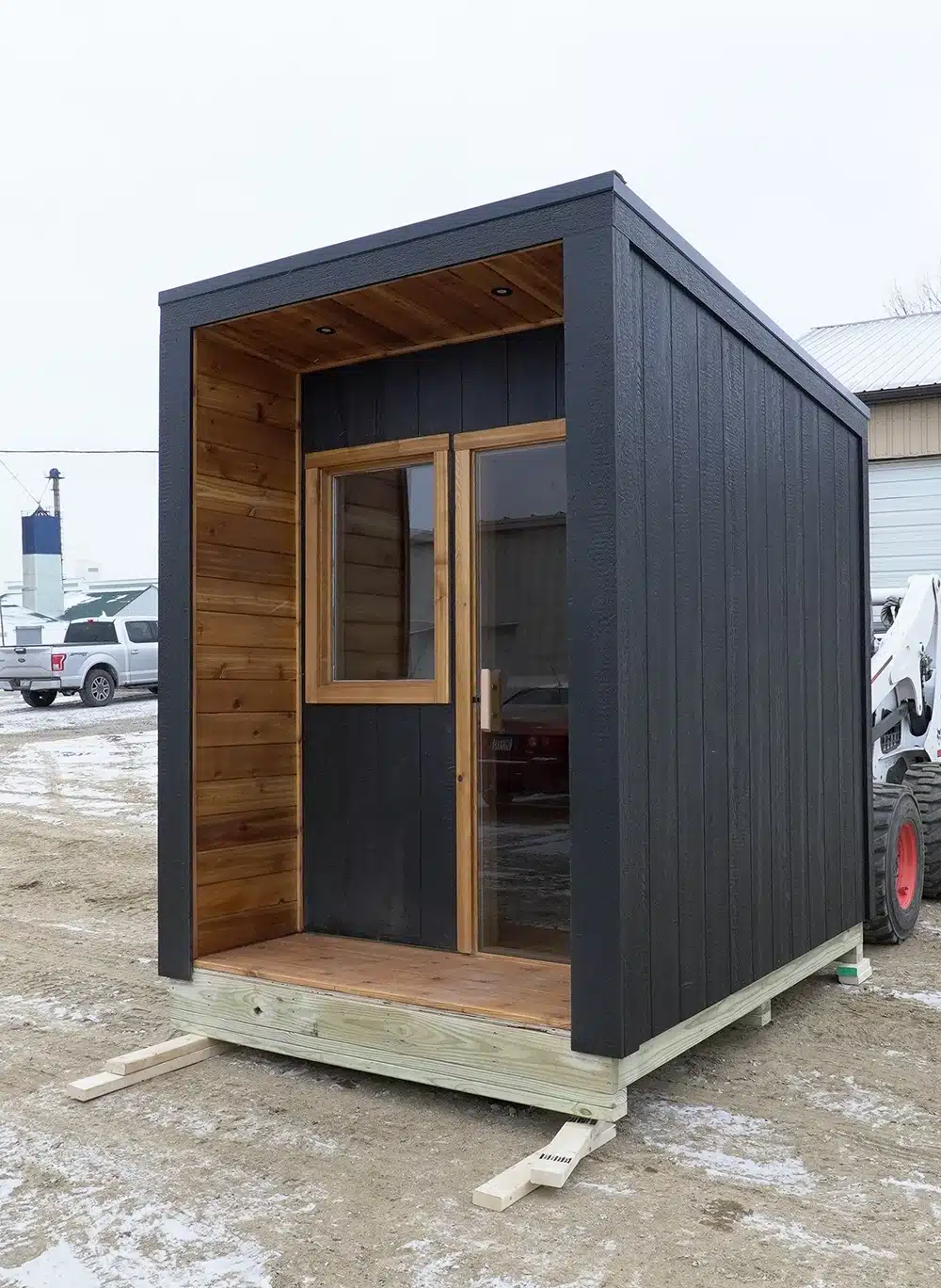 custom outdoor sauna painted black with knotty cedar wood. Porch out front.