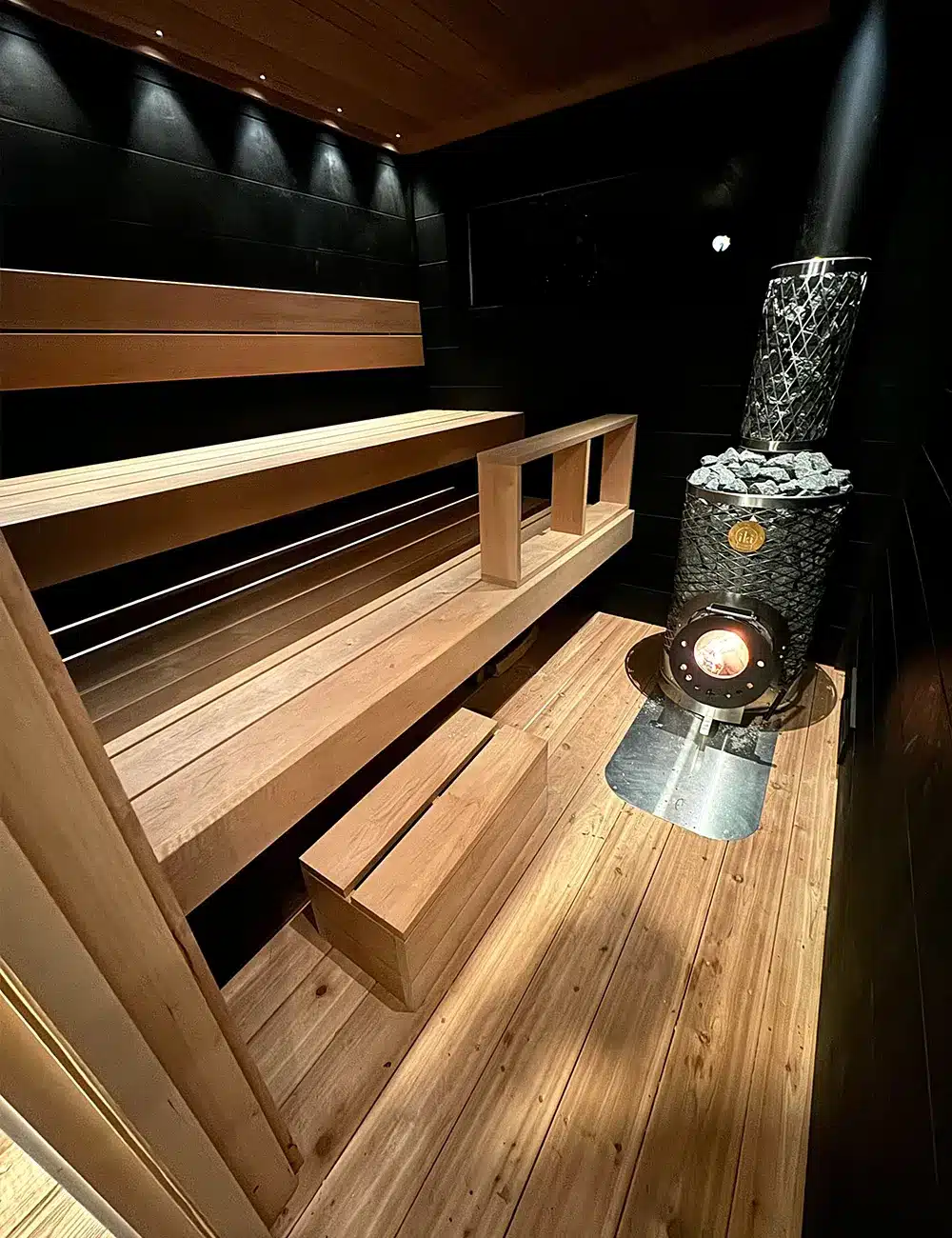 8x12 black taika outdoor sauna with fire in stove